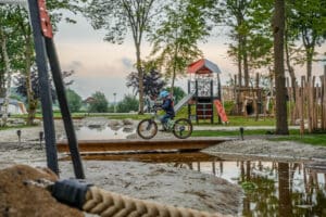 jongen op fiets bij zand-waterplek - Natuurlijk Wedderbergen – de grootste speelse waterkreek van Nederland
