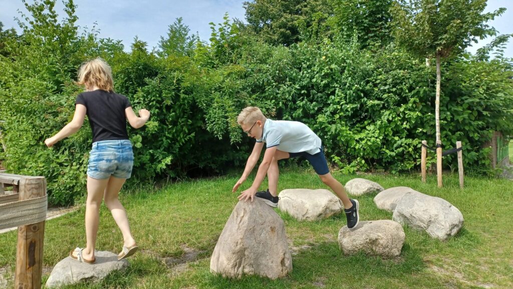 herinrichting groenblauw schoolplein met grote zwerfkeien en natuurlijke materialen